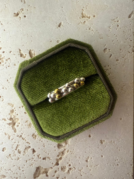 Green textured patch with a silver ring on a beige surface