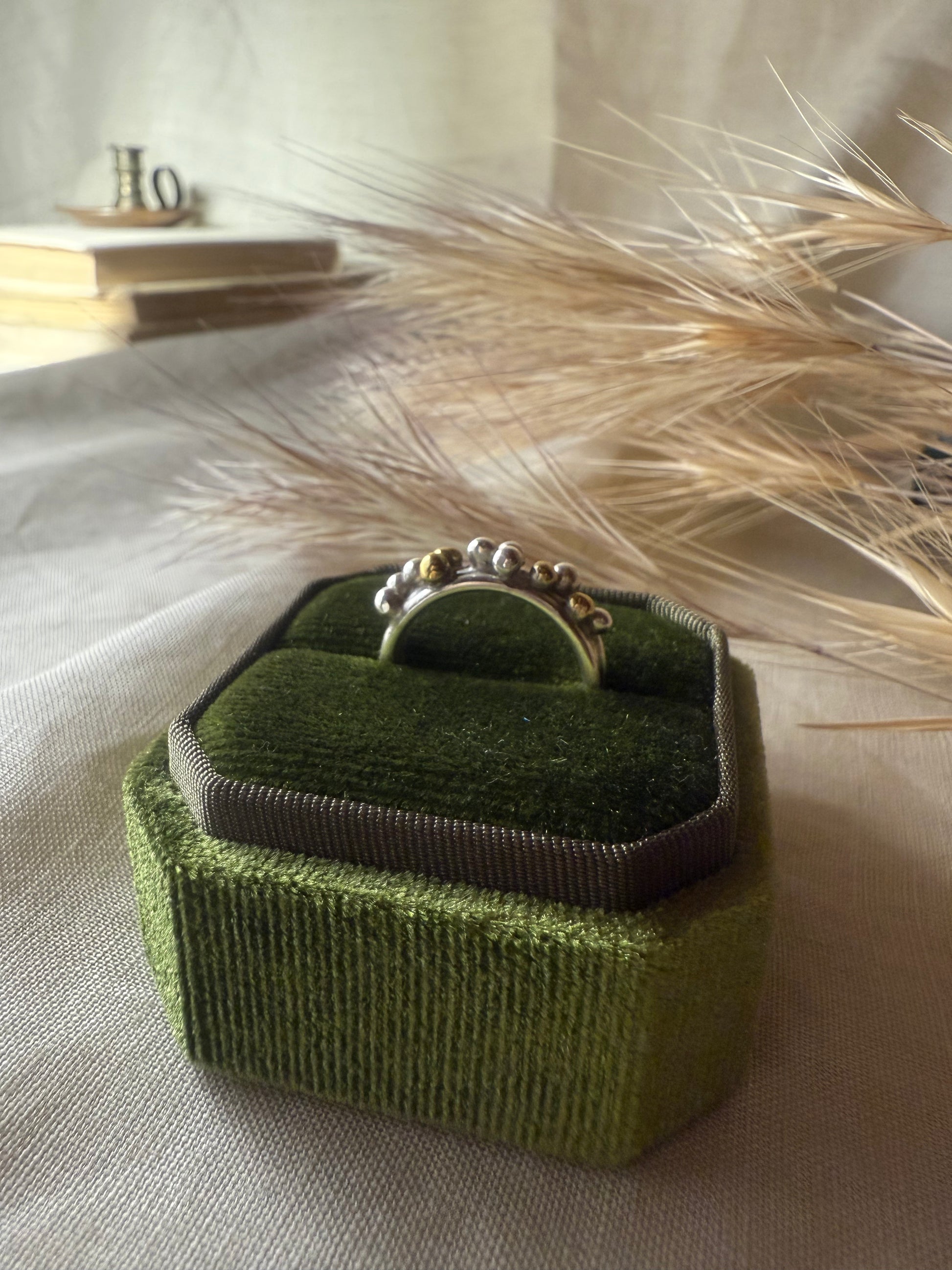 Green jewelry box with a ring on a neutral background