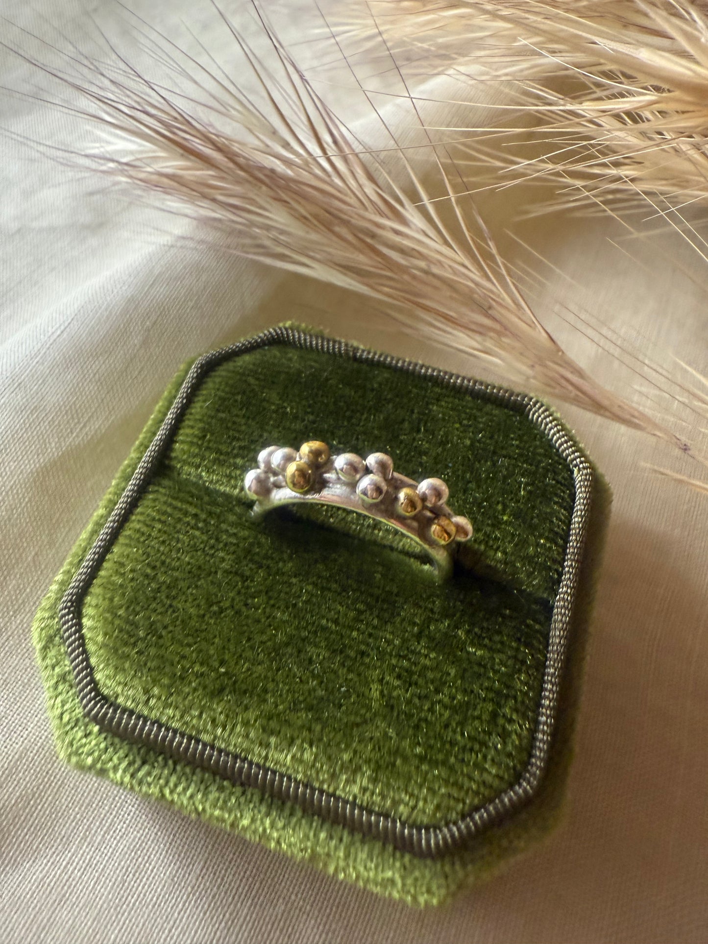 Silver ring with granules on a green textured surface